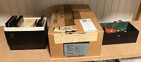 Photo of 12 microscope slides in black storage box, cardboard box labeled Corning containing test tubes, and green box with vintage medical items.