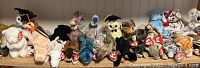 Photo showing approximately 27 TY Beanie Babies arranged on shelves in various colors and animal characters.