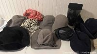 Overview of 12 vintage mid-century women’s hats in various shades of gray, black, and beige with some patterned scarves included.