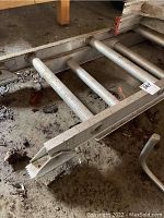 Close-up of ladder end showing extension bracket and rounded rungs.