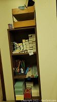 Wooden shelving with multiple shelves of pencil lead boxes, writing instruments and note card stacks