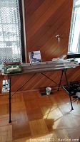 Full view of knitting machine set up on tripod stand with yarn feeder and manual behind