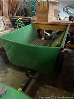 Front-angle view of green steel bed and black tongue attached to tractor