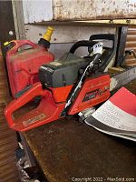 Chainsaw, red gas can and manual on workbench