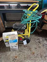 Full view of Karcher pressure washer with coiled hose, boxes and spray wand