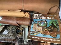 Shelf with multiple leather rolls of various colours and a book titled "Ideas for Leather Projects No. 2"