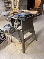 Side view of Rockwell Beaver 10" tilting arbor saw on metal stand with motor and cord visible.