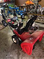 Full side view of red Toro snowblower showing housing, chute, engine and handles