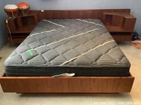 Front view of platform bed with headboard, attached nightstands, and mattress installed