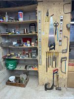 Wide view showing diverse assortment of tools on shelves and wall-mounted board including hand saws, levels, files, scissors, spray cans, and containers.