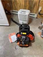 Tanaka Pro Force backpack blower and Frigidaire humidifier placed on floor with instruction manual.