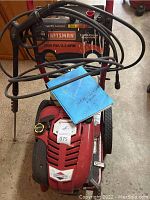 Front view of red Craftsman pressure washer showing engine cover, hoses, detergent tanks and wheels