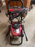 Front view of entire pressure washer showing handle, engine, hose and wheels