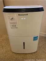 Front view of white Honeywell dehumidifier with Energy Star label and water level window in tank.