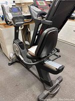 Rear-angle view of recumbent bike showing seat, backrest, pedals, and frame.