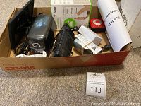 Overview showing box with eTape16 instruction manual, Belkin Wemo light switch in box, and miscellaneous electronics including an electric pencil sharpener and a Nixplay device.