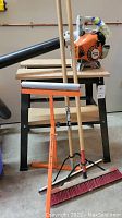 Entire lot showing Stihl BG 50 blower on top of Craftsman saw table with adjustable pedestal roller and cleaning tools including push broom and floor squeegee leaned against table.