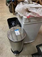 Kenmore trash compactor with several trash cans and bags on top, showing overall lot contents