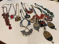 Eight statement necklaces laid out on white surface, showing colors, styles and general condition