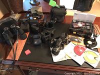 Overview of all lot contents including cameras, binoculars, batteries, cases and manuals