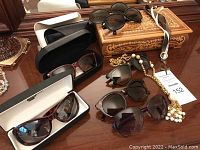 Overview photo showing the vintage wooden music box, assorted sunglasses and cases, and vintage jewelry pieces.