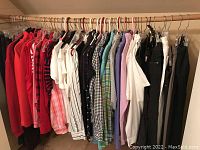 Wooden clothes rod with assorted tops and blouses in red, white, black, green, purple and checkered patterns