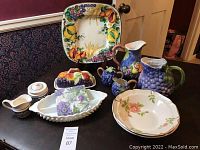 Photo showing entire lot of colorful ceramics and vintage blue hobnail Fenton bowl on table.