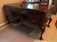 Full front angle view of the Ethan Allen solid cherry Chippendale desk showing carved ball and claw feet, multiple drawers and brass hardware.