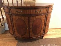 Front view of half-moon shaped console cabinet showing drawers, doors and veneer pattern