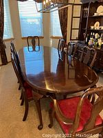 Full view of oval dining table extended with eight chairs arranged around it