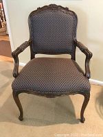 Full front view of the armchair showing carved crest, arms, seat and legs