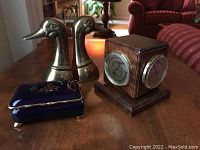 Overall view of the weather station cube, duck bookends, and blue porcelain trinket box on wooden table