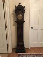 Full front view of black chinoiserie grandmother clock showing overall form and finish.