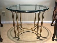 Full front view of round glass top table on brass frame