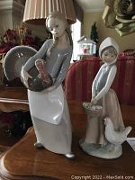 Two Lladro figurines together: girl holding turkey and girl with chicks and chicken