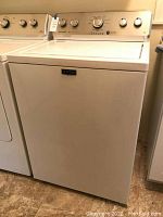 Maytag white top load washing machine showing front and side with control panel on top, knobs, and brand label.