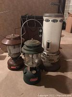 Group shot: two lanterns, Valor 207 heater/stove and electric space heater on concrete floor