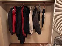 Photo of multiple women's coats and jackets hanging on closet rail, mostly dark colors with one beige item visible, plus two umbrellas hung on right.