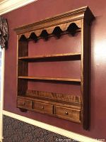 Front view of the wooden shelf showing 3 shelves, slotted grooves for plates, and 1 large drawer with 3 handles below.