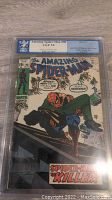Front cover photo showing Spider-Man holding a man on a ledge with graded PGX 5.0 label visible.