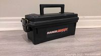 Closed black plastic ammo/storage can with RANGEMAXX label on the side, metal latch, and handle on lid.