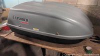 Side view of the gray Karrite Explorer car top cargo carrier placed on a bench, displaying the branding and condition.