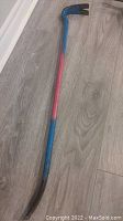 Full length view of crowbar showing flat chisel end and claw end with blue and red painted handle
