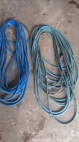 Two long blue contractor grade electrical extension cords coiled on floor, showing full length with plugs.