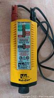 Front view of yellow Ideal Vol-Con voltage tester showing scale, labels and attached black and red probes.