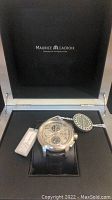 Inside view of open Maurice Lacroix presentation box showing watch on cushion with hang tags