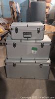 Three stacked silver metal storage boxes with latch closures, black reinforced corners, and chrome handles.