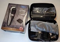 Photo shows wired Cosyonall hair and beard clipper with adjustable blade alongside comb attachments, a styling comb, charger cable, all contained within a black storage case and the product box.