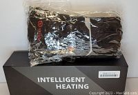Photo of Savior Intelligent Heating rechargeable heated gloves in black, packaged in plastic, placed on top of the original box labeled 'INTELLIGENT HEATING'.