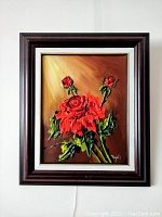 Framed impasto painting of red roses with rich application of red and green paint on a brown background, signed by Pejril.